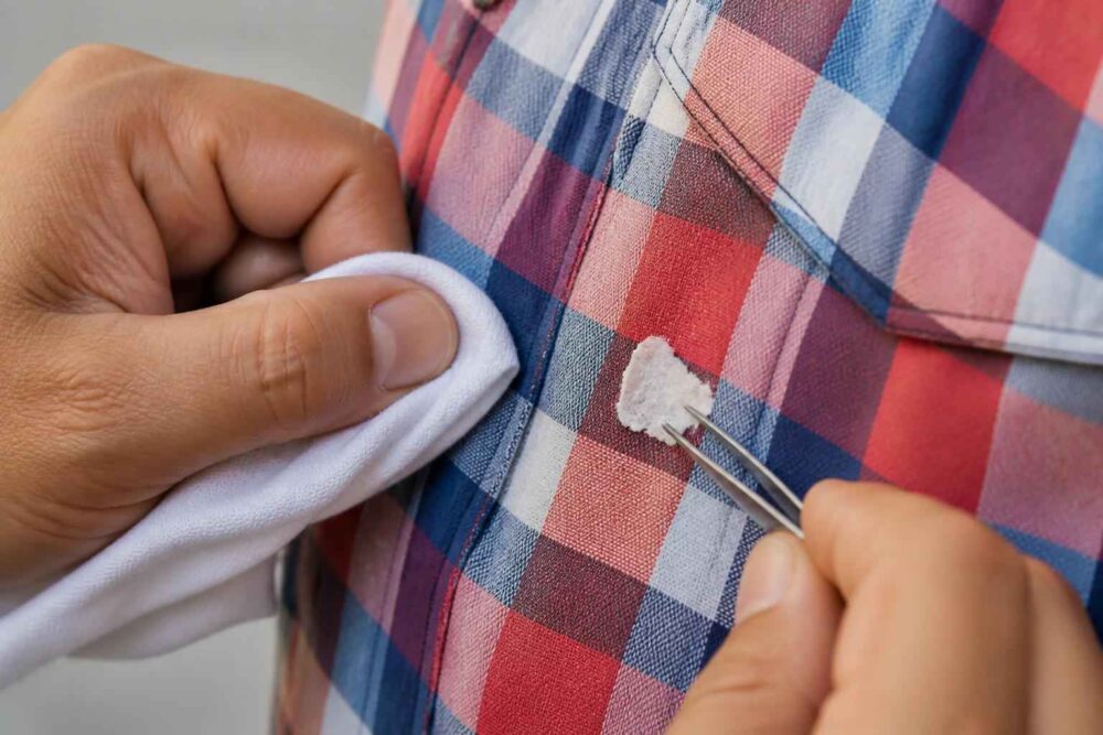 Usuwanie plamy z kraciastej koszuli za pomocą pęsety i białej ściereczki